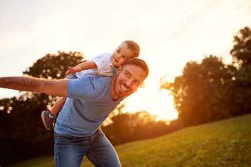 Happy young father with son in park - obrazy, fototapety, plakaty