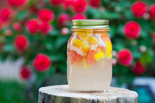 Fresh lemonade from lemon and grapefruit and orange in a jar on a wooden stump.