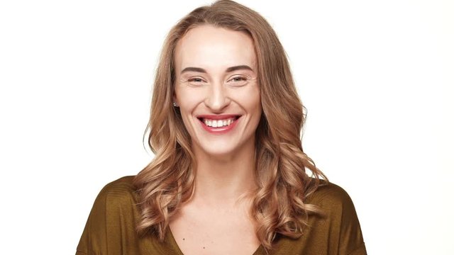 Beautiful middle-aged Caucasian female with long light brown hair smiling on white background in slowmotion
