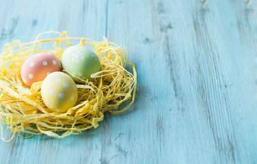 Easter eggs in a nest on a blue, wooden background. Banner, top view