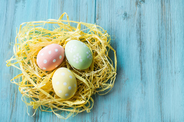 Easter eggs in a nest on a blue, wooden background. Banner, top view