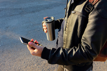 Man holding mobile phone and thermos cup, travel mug