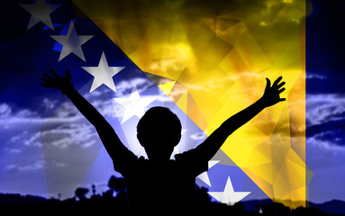 Young man raising his hands on a sunset background with a flag background - 139371584