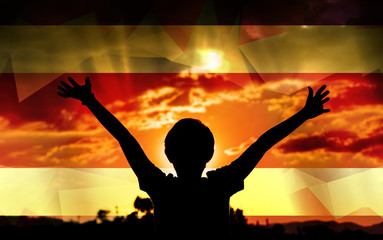 Young man raising his hands on a sunset background with a flag background - 139372156