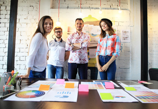 Portrait of happy young people in a meeting looking at camera and smiling. Young designers working together on a creative project