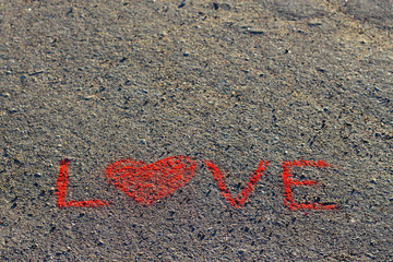 Word LOVE written on the asphalt, ground. Red color of chalk