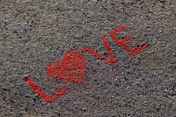 Word LOVE written on the asphalt, ground. Red color of chalk