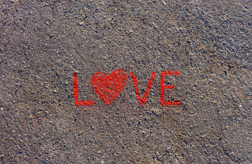 Word LOVE written on the asphalt, ground. Red color of chalk