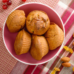 Freshly baked homemade muffins with cranberry raisins and nuts in the pink bowl.
