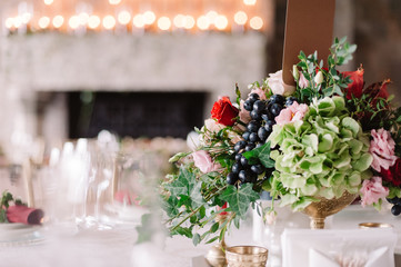 Wedding table decoration with the red and pink flowers, grape and greenery