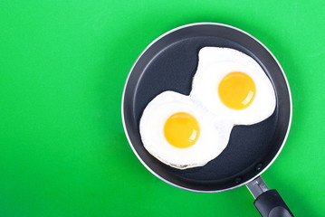 fried eggs in a pan two eggs on a green background