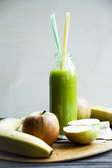 fresh juice from raw apples and bananas in a transparent bottle with a yellow and green tubes
