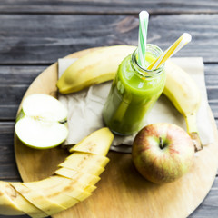 fresh juice from raw apples and bananas in a transparent bottle with a yellow and green tubes