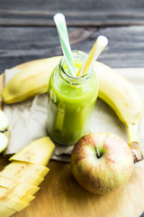 fresh juice from raw apples and bananas in a transparent bottle with a yellow and green tubes