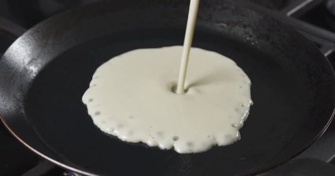 Slow motion of preparin blini or crepes batter pouring on hot pan, 4k 60fps prores footage