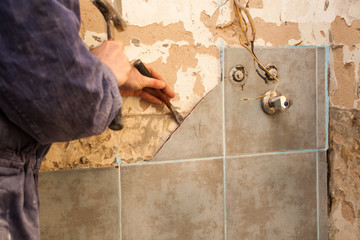 Flat renovation, ceramics, master robbing old tiles in the bathroom with a hammer