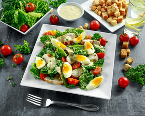 Fresh healthy Caesar salad with chicken, eggs, tomatoes, Cheese and Croutons on white plate
