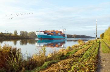 Containerschiff passiert den Nord-Ostsee-Kanal im herbstlichen Morgenlicht