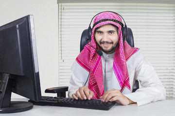 Muslim operator working with computer and headphone