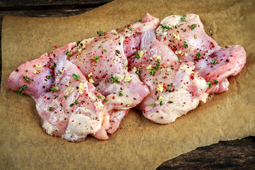 Ready to cook free range raw boneless skinless chicken thighs on paper seasoned with sea salt,...