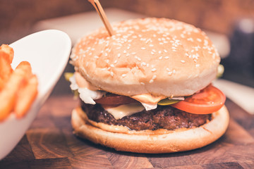 Burger with fresh tomato, cheese, meat and french fries. Selective focus