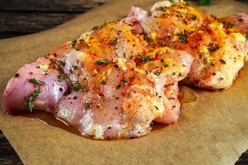 Ready to cook free range raw boneless skinless chicken thighs on paper seasoned with sea salt, garlic and pepper