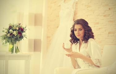 Obraz na płótnie Canvas Beautiful bride drinking coffee before wedding