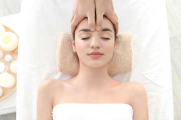 Fototapeta na wymiar Beautiful young woman receiving facial massage in spa salon
