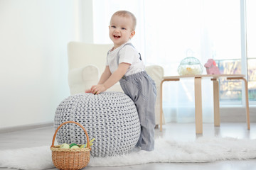 Cute little baby playing with ottoman at home