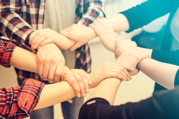 A group of young people hold strong hands.