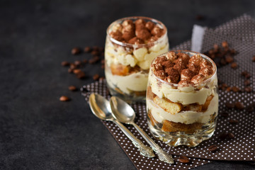 Classic tiramisu in a glass jar on a black background 