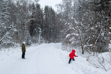 mother and daughter walking along the road in winter forest