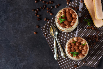 Classic tiramisu in a glass jar on a black background 