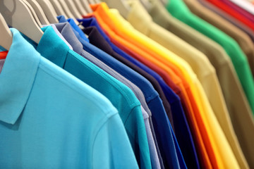 Row of men's polo shirts in wardrobe or store - obrazy, fototapety, plakaty