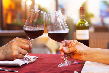 couple drinking wine in restaurant, close up of hands with glasses, happy moment