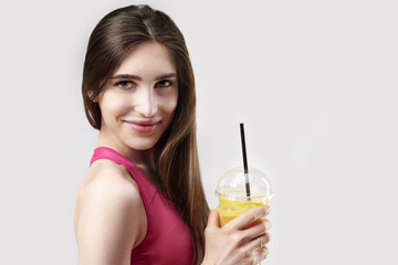 Portrait of sporty young caucasian woman holding plastic glass of orange juice