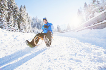 sleigh, winter holiday snow activity, young man having fun sledding