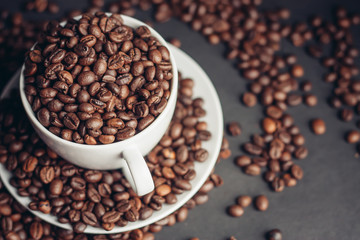 Coffee beans in a cup and in a white saucer
