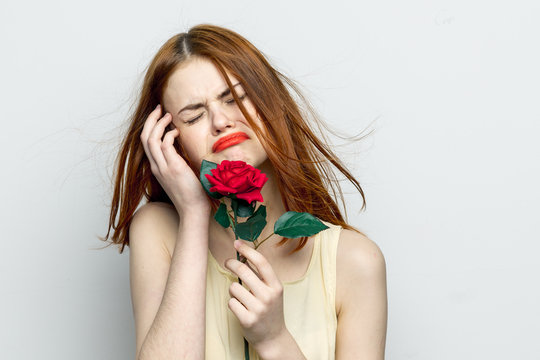 upset woman crying on a gray background, red flower