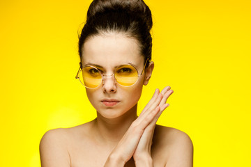 attractive brunette with glasses on a yellow background