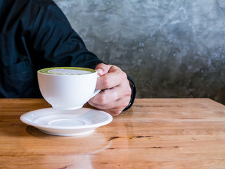 Asian man holding a cup of hot matcha latte. Asian man holding a cup of hot green tea latte.