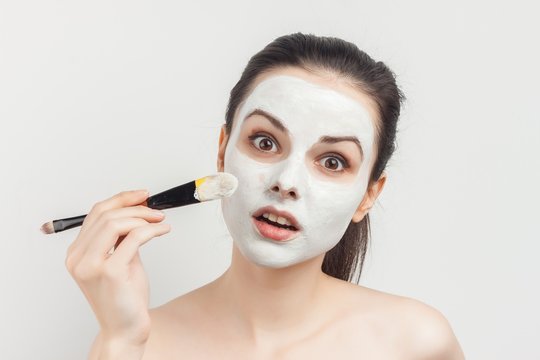 Woman with brush in her hands and cream on her face, clean face
