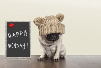 cute pug puppy dog with bad monday morning mood, sitting next to blackboard sign with text happy monday, copy space