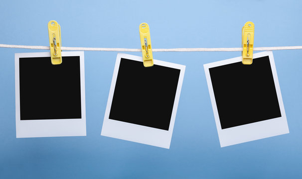 three blank insta photo frames on clothes pins on rope isolated on blue background