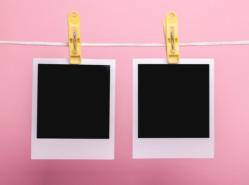 two blank insta photo frames on clothes pins on rope isolated on pink background