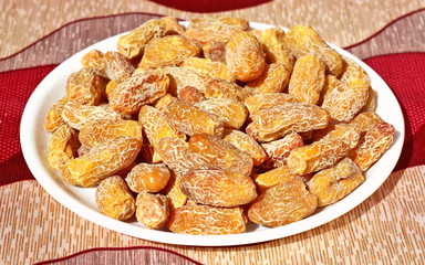 Raw date-palm isolated on the red-grey background in white plate.