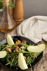 salad of arugula, nuts, apples and prunes, salt, pepper and olive oil in a bottle.