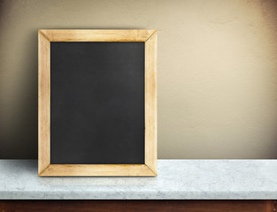 Blank blackboard on blue marble table at yellow concrete wall,Template mock up for adding your design and leave space beside frame for adding more text.