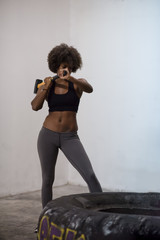 black woman workout with hammer and tractor tire