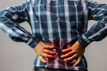 Men with low back pain on a gray background / medical and health concepts.